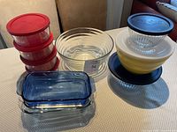Photo showing blue rectangular bakeware, nested yellow and clear mixing bowls, round glass containers with red and black lids.