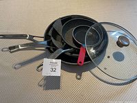 Photo showing all four frying pans stacked with the glass lid placed on top, felt pan protectors visible between pans