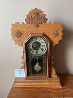 Front view of the antique wooden mantel clock showing the carved detail and clock face.