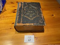 Front cover photo showing worn black leather bound Holy Bible with gold embossed title and decorative shield design.