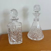 Front view of both crystal decanters showing shapes and stoppers