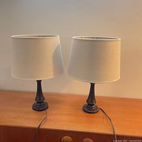 Two matching table lamps on surface, both bases and shades visible