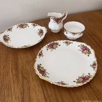 Full set showing two plates, creamer, sugar bowl on table
