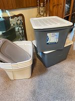 Pile of two grey totes stacked with white lids and three off-white totes nested beside them