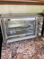 Front view of Black+Decker air fryer toaster oven showing glass door, control knobs and interior rack