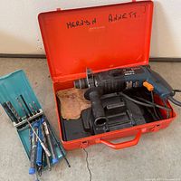 Open red case with Bosch rotary hammer drill and bit holder visible