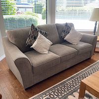 Full view of graphite grey three-seat sofa with four pillows