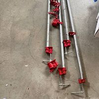 Four long pipe clamps laid on concrete floor