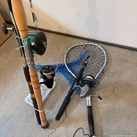 Group shot of three rods with reels, landing net and tackle box