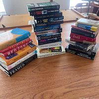 Two stacks of assorted hard and soft cover books on table