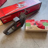 Craftsman hedge trimmer, blade, handle and box beside Milwaukee drill box