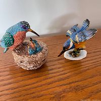 Two enameled hummingbird figurine trinket boxes on wood surface