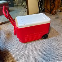 Full view of red Igloo Wheelie Cool cooler on wheels with lid closed