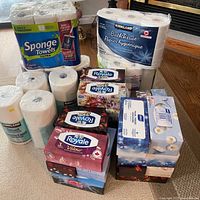 Full lot view showing bath tissue pack, SpongeTowels pack, loose Kirkland paper towel rolls and stacked tissue boxes