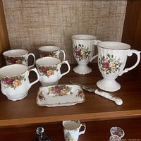 Shelf view showing four standard mugs, candy dish, cheese knife, two pedestal mugs