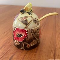 Front view of honey pot showing poppy design and bee on lid