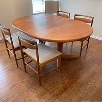 Oval teak table with four chairs around it