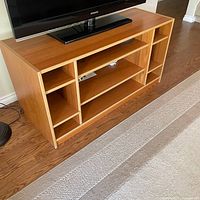 Front view showing entire console with shelving layout and TV on top