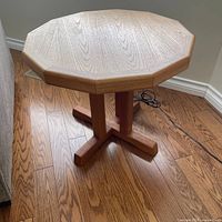 Full view of octagonal teak side table next to sofa