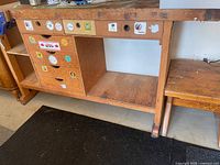 front view of wooden workbench showing drawers, open shelf and stickers