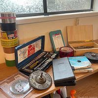 Overall view of socket set, tapes, abrasive wheels, wooden box and other accessories on shelf