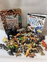 Pile of assorted animal figurines with two hardcover books in background