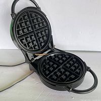 Waffle maker open showing non-stick grid plates and hinge