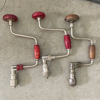 three vintage hand brace drills laid side by side