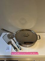 Overview of saucepan, lid and utensils alongside a ruler