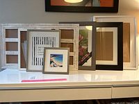 Seven assorted picture frames arranged on white surface showing various sizes and styles.