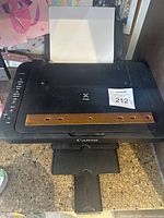 Canon Pixma MG3029 printer showing paper input tray with paper loaded, top control buttons and paper output tray extended.