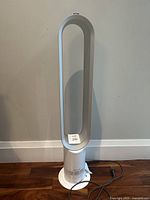 Full-height front view of white bladeless fan on wooden floor against wall