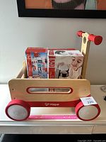 Wooden walk-along push cart labeled with lot number 220, showing natural wood and red color design