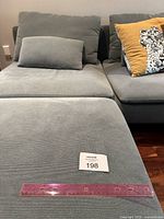 Close-up of ottoman top with ruler and lot tag 198