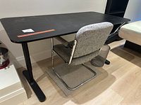 Side view of Ikea Bekant black desk with upholstered office chair with chrome frame and cantilever base