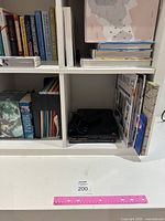 Close-up of lower compartments of the Kallax unit with various books stored inside, showcasing the white shelving squares.