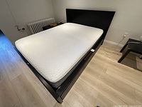 Full perspective of assembled Ikea MALM queen bed with Endy queen mattress in bedroom environment.
