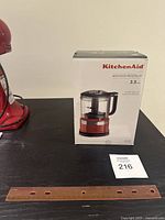 KitchenAid Mini Food Processor in original box on a black surface with a ruler for scale