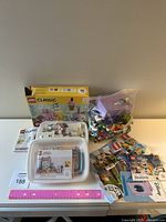 Full view of the lot on table showing box of LEGO Classic 10178, two plastic containers with LEGO pieces and instruction manual, and various LEGO polybags scattered on the table.