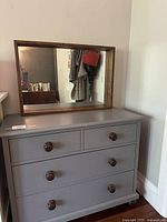 Full view of grey dresser with wooden-framed mirror above.