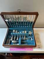 Open wooden box with Heirloom Sterling flatware arranged in blue velvet interior