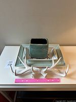 Top view of aqua melamine tray, collectible Norwegian 'Lotte' tray with blue floral bird design, aqua crackle vase, and decorative hanging antlers on white surface with pink ruler for scale.