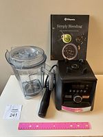 Blender base, pitcher, lid, tamper and recipe book laid out