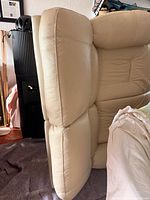 Side profile showing beige leather upholstery and thick cushioning on loveseat