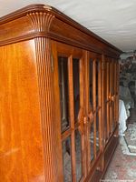 Front angled view of cherry display cabinet showing glass doors and carved pulls