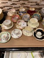 Wide view of all twelve assorted teacup and saucer sets arranged on cardboard surface