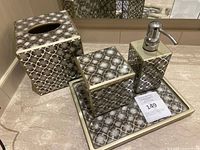 Four-piece bathroom accessory set arranged on a bathroom counter, showing all items and their design pattern.