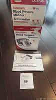 Boxed Omron Automatic Blood Pressure Monitor Model HEM-741CAN with instruction manual on tiled floor.