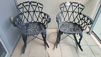 Two matching cast iron rocking chairs with decorative openwork on balcony floor