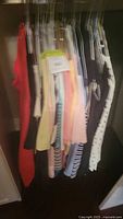 Photo of assorted casual wear clothing items on hangers, mix of colors and styles.